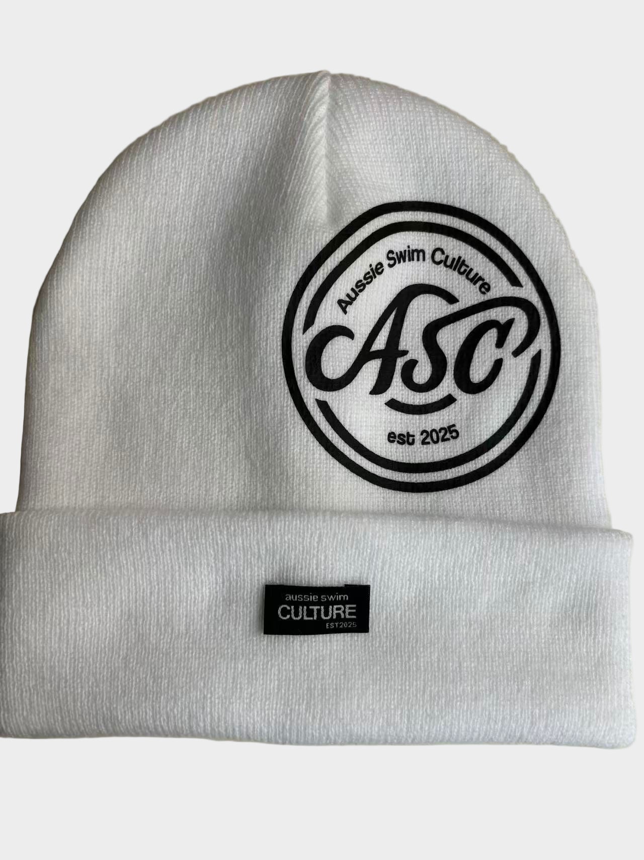 White beanie with black logo and text on a neutral background