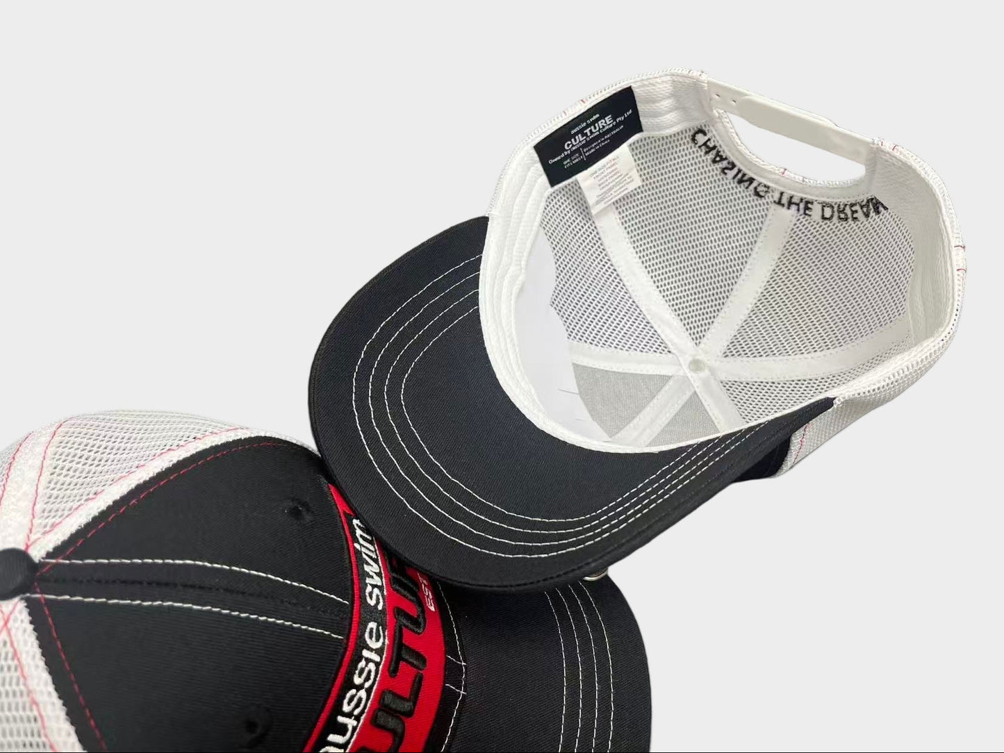 Two caps with mesh backs on a gray background